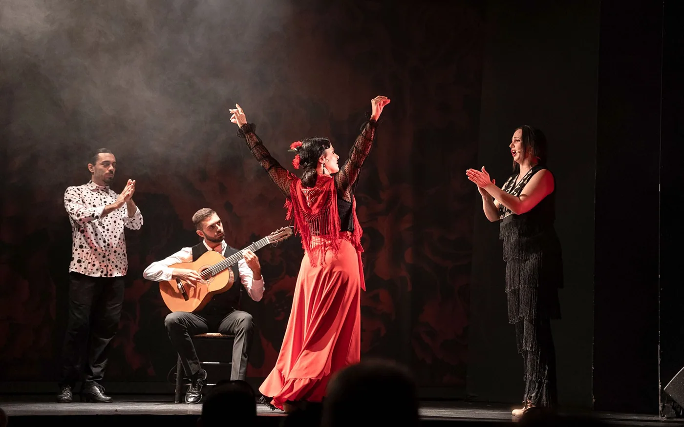 Flamenco dancer in a red skirt with accompanying musicians